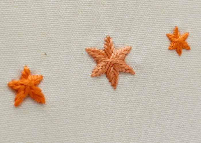 Punto stella intrecciato - ricamo di stelle riempite con filo arancione